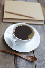 coffee with wooden spoon and notebook on wooden table