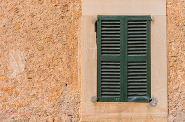 Fototapeta na wymiar Old rustic stone wall with mediterranean green shutters