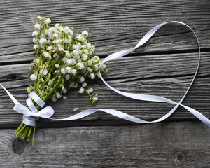 lilies of the valley with a ribbon in the form of heart on a wooden Board