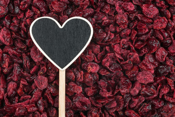 Obraz na płótnie Canvas Pointer in the form of heart lies on dried cranberries