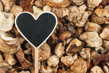Pointer in the form of heart lies on dried mushrooms