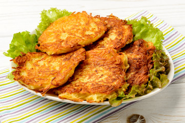 Potato pancakes on white wooden table.
