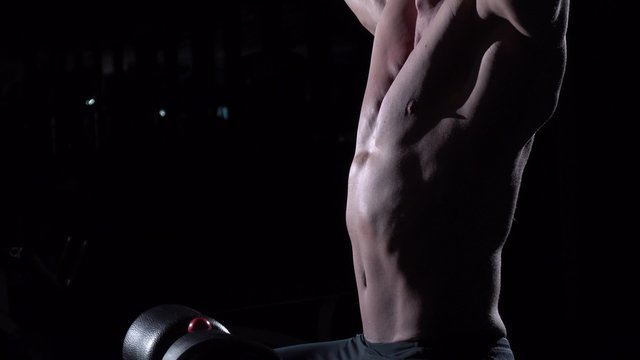 Torso of young man doing lats pulldown exercises to front in gym