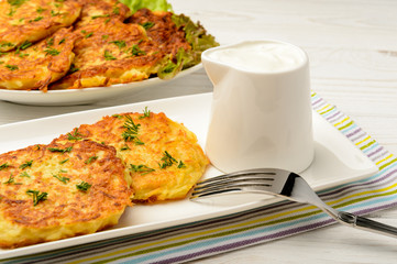 Potato pancakes on white wooden table.