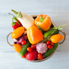Fresh vegetables in metal colander over white.