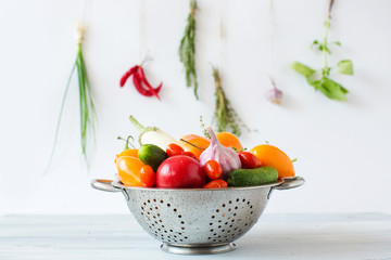 Clean vegetables in a metal colander on a background of spices.