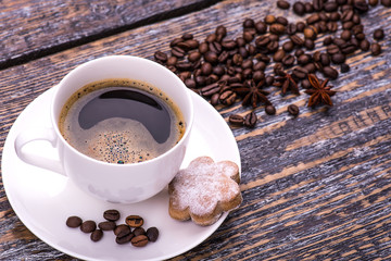 Cookies and biscuits in the shape of a heart for Valentine's day on a wooden background. A cup of fragrant delicious, invigorating coffee, coffee beans, spices.