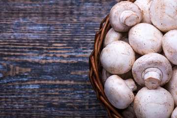 Mushrooms in a basket on a wooden table background.