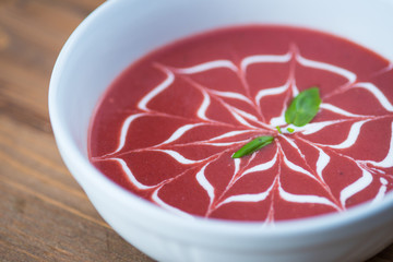 Beetroot soup served in a ceramic bowl on wooden board