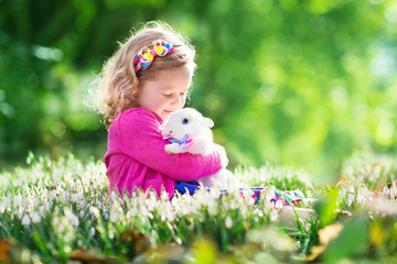Little girl playing with bunny on Easter egg hunt