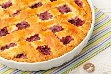 Cherry pie on white wooden table.