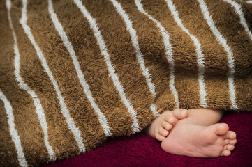 Baby feet on red coverlet. Macro. Close-up.selective focus
