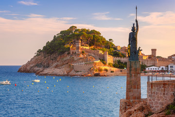 Statue of Minerva on the enbankment, Fortress and Badia de Tossa bay in Tossa de Mar on Costa Brava at summer sunset, Catalunya, Spain