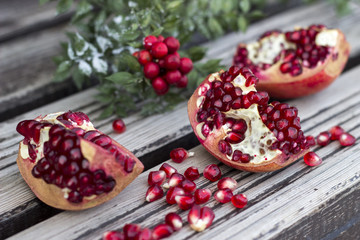 Juicy pomegranate fruit and red flower over wooden table 