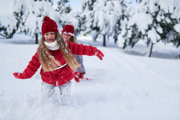 daughter with mother play in snow-covered park