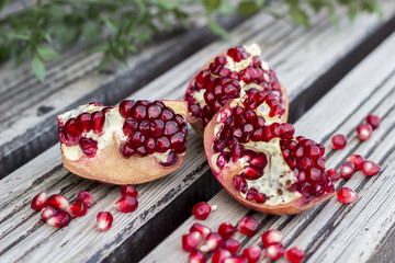 Juicy pomegranate fruit and red flower over wooden table 