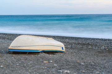 Boat turned upside down lying on pebble beach