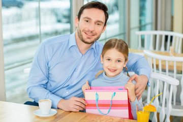 Obraz premium Joyful father sitting and hugging dear kid at the cafeteria.