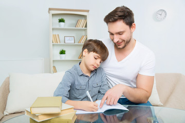 Fototapeta na wymiar Interested young father is helping son to solve homework