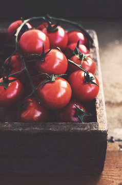 Ripe cherry tomatoes in rustic wooden crate