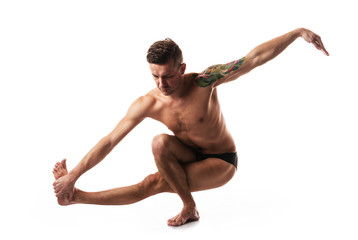 young strong man doing yoga and gymnastics, balance
