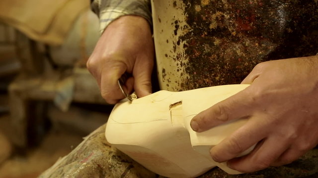 Clog maker is cutting decoration in clog with a gouge