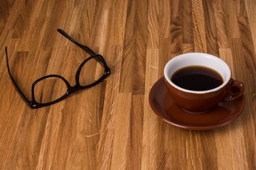 Nerdbrille und Kaffeetasse auf Holztisch
