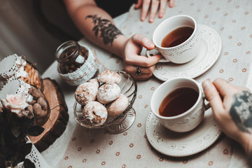 a guy and a girl with two cups of tea at a beautiful table with gingerbread