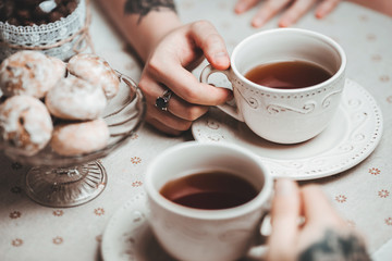 a guy and a girl with two cups of tea at a beautiful table with gingerbread