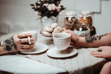 a guy and a girl with two cups of tea at a beautiful table with gingerbread