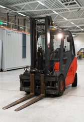 Orange forklift loader in the modern warehouse.