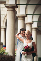 Beautiful couple, bride and groom posing on old balcony with column