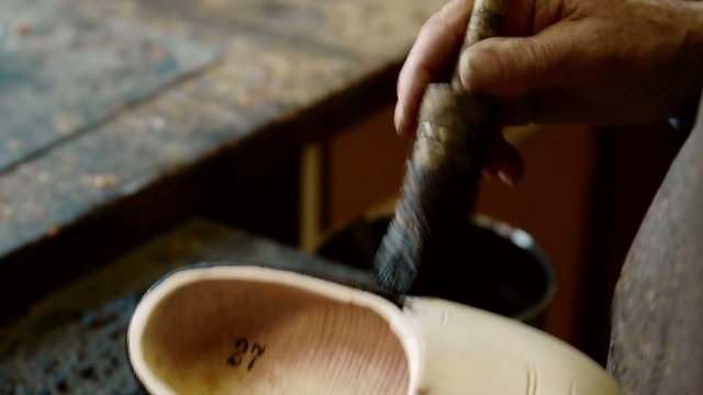 Clog maker is painting a clog black