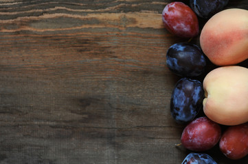 Peaches and plums on dark wooden table.