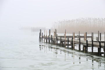 Holzsteg im Nebel im gefrorenen See