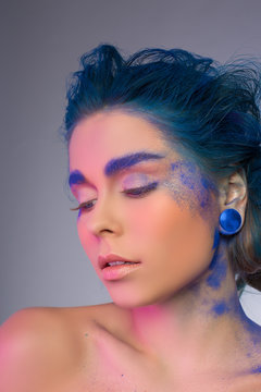 Gorgeous young woman with blue hair, earrings, makeup