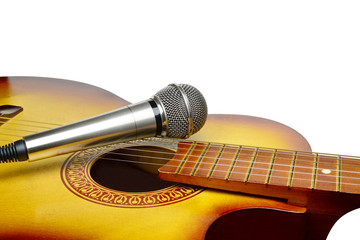 Silver microphone lays on acoustic guitar