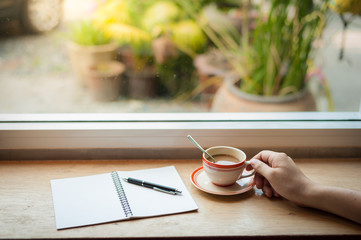 writing on notebook with coffee cup