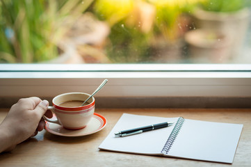 writing on notebook with coffee cup