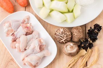 Raw chicken legs with fresh vegetable on wooden.