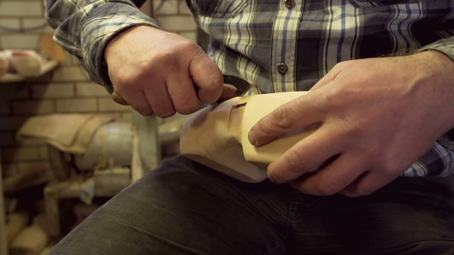 Clog maker is cutting decoration in clog with a gouge