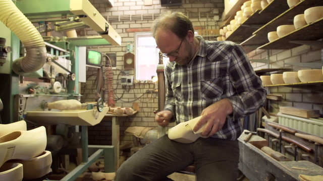 Clog maker is cutting decoration in clog with a gouge