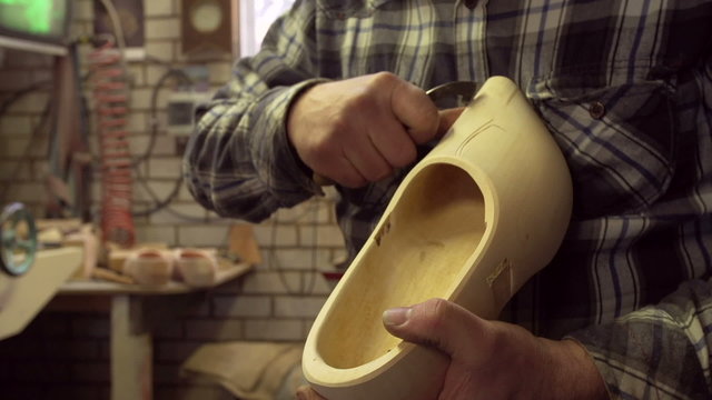 Clog maker is cutting decoration in clog with a gouge