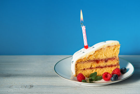 Slice of birthday cake with candle and fresh berries