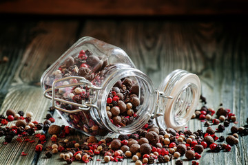 Mix from five peppers in a glass jar on old wooden table, select