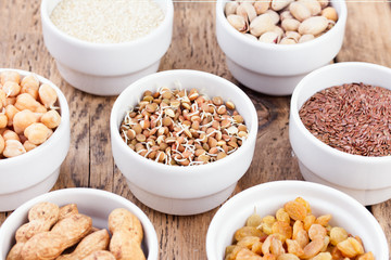 Bowls of various legumes and seeds. Lentils, sesame seeds, pistachio nuts, flaxseed, raisins, peanuts, chickpeas.  