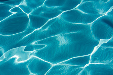 Background of rippled pattern of clean water in a blue swimming pool