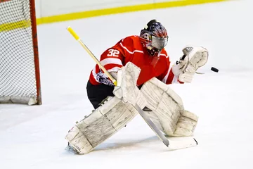 Tuinposter Hockey goalie in generic red equipment protects gate © Lsantilli