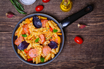 pasta with sausage, peppers, cheese and herbs on a wooden background