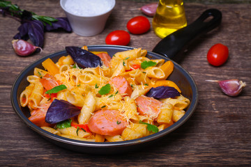 pasta with sausage, peppers, cheese and herbs on a wooden background